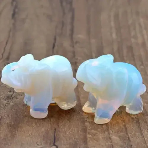 Two translucent opal elephant figurines with a soft, iridescent sheen that shifts between pale blue and creamy white.