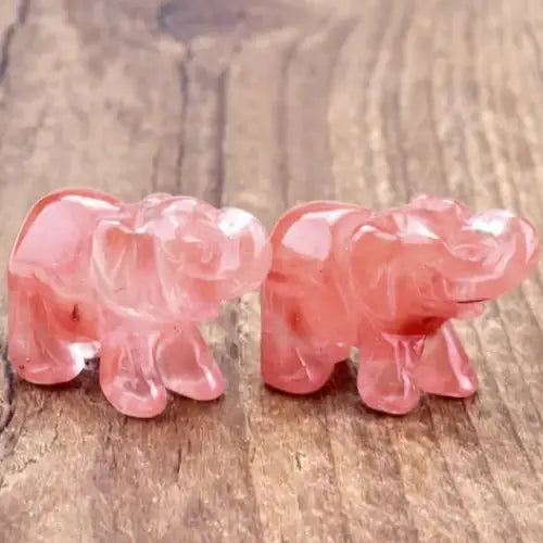 Two translucent pink rose quartz elephant figurines, intricately carved with smooth, glossy surfaces.