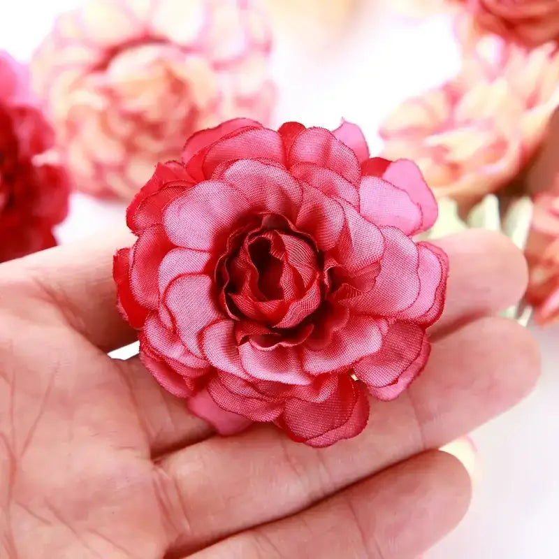 A vibrant red fabric flower with layered petals, crafted from a sheer, lightweight material.
