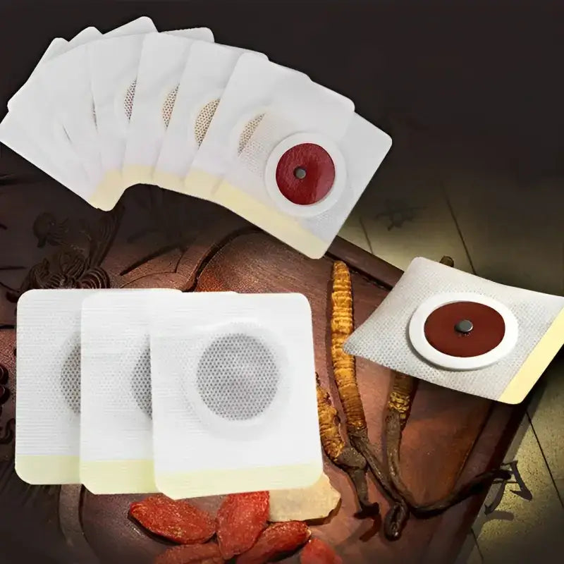 White square adhesive patches with circular mesh centers and red or brown central discs, designed for traditional herbal therapy.