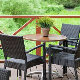 Black wicker patio table with a round wooden top and silver metal base