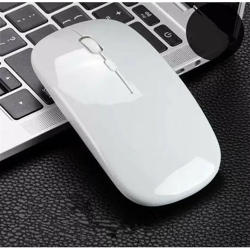 A sleek white wireless mouse with a glossy finish and minimalist design, resting beside a laptop.