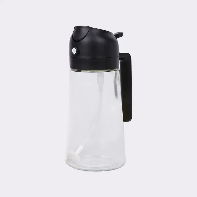Clear glass oil dispenser with a black plastic lid and handle.