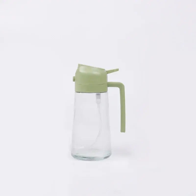 Clear glass oil dispenser with sage green plastic lid and handle.