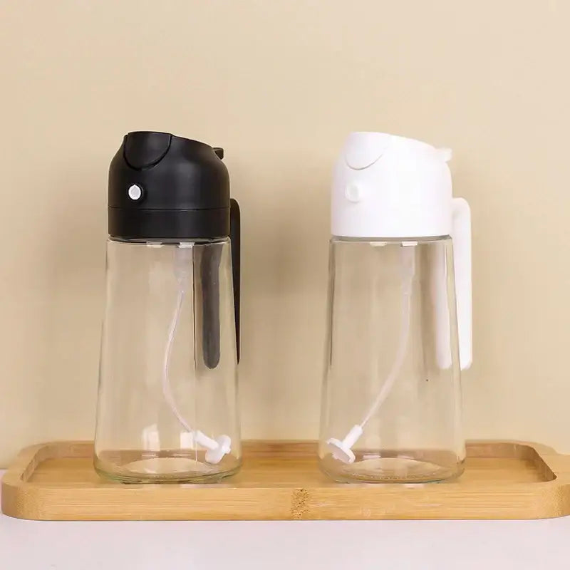 Two clear glass oil dispensers with black and white plastic tops, each featuring a built-in pump mechanism.