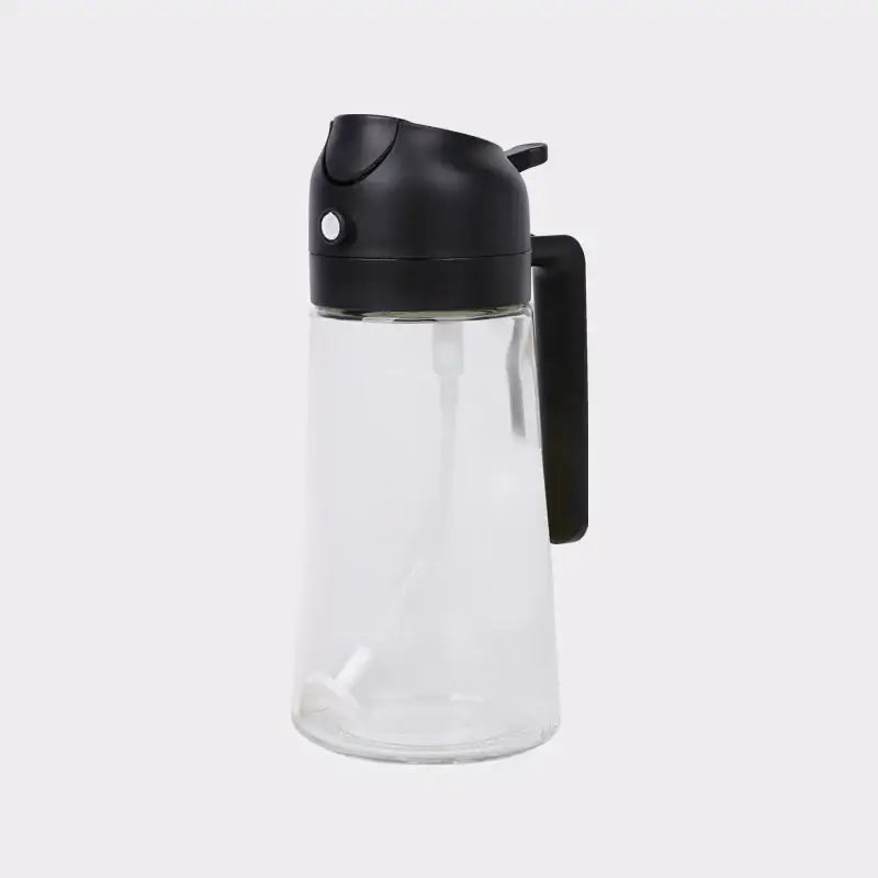 Clear glass oil dispenser with a black plastic lid and handle.