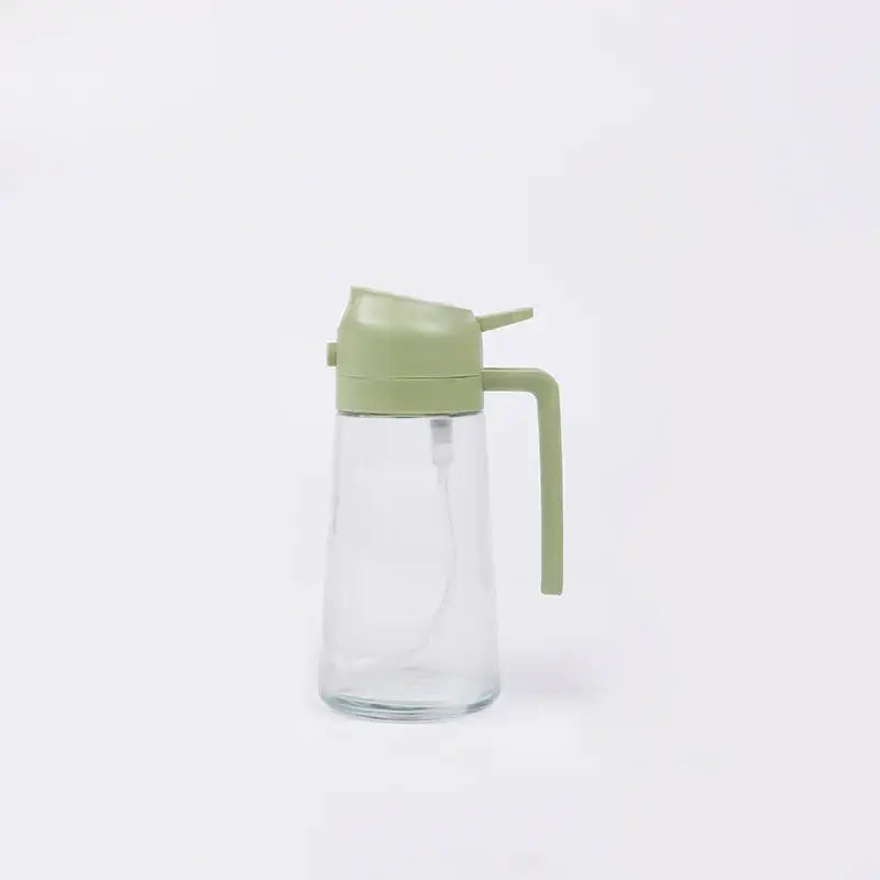 Clear glass oil dispenser with sage green plastic lid and handle.