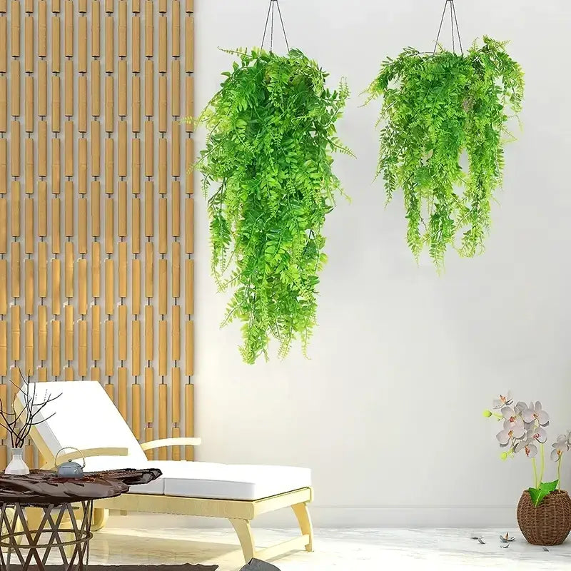 Two hanging artificial green ferns with lush, leafy fronds suspended by black cords.