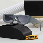 Gray rectangular-framed sunglasses with gradient gray lenses, resting on a black textured case.