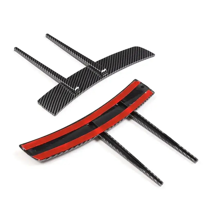Black carbon fiber car side mirror cover trim with red adhesive backing.