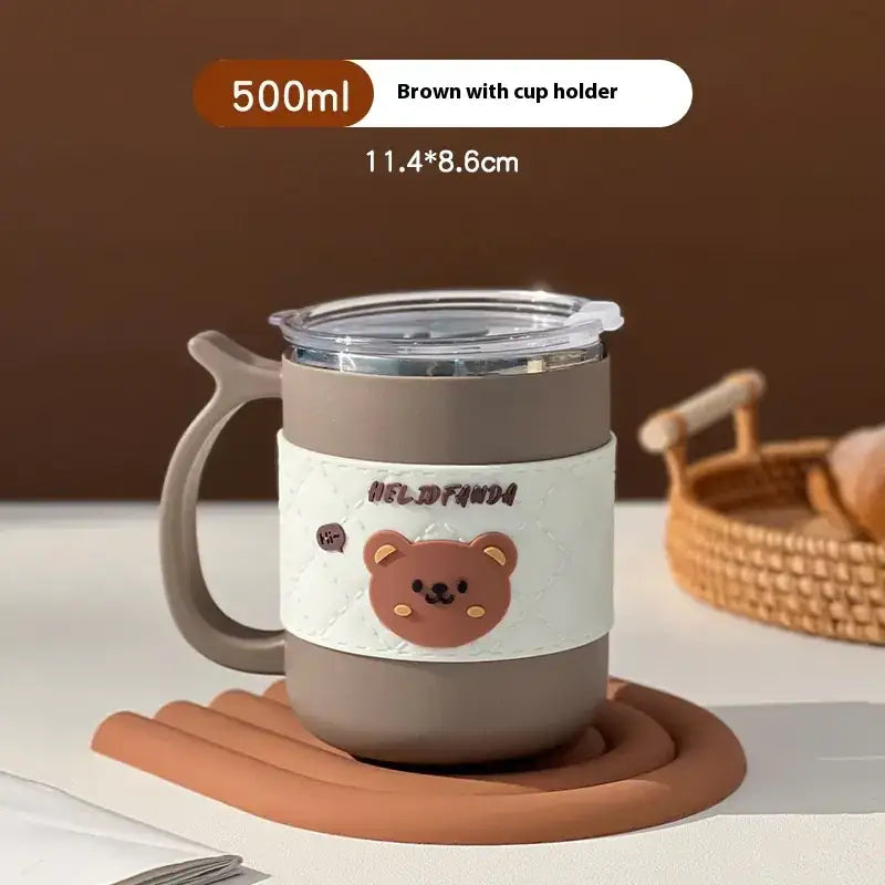 Brown 500ml insulated mug with a cute bear design on its white silicone band and a clear lid, featuring an integrated cup holder handle.
