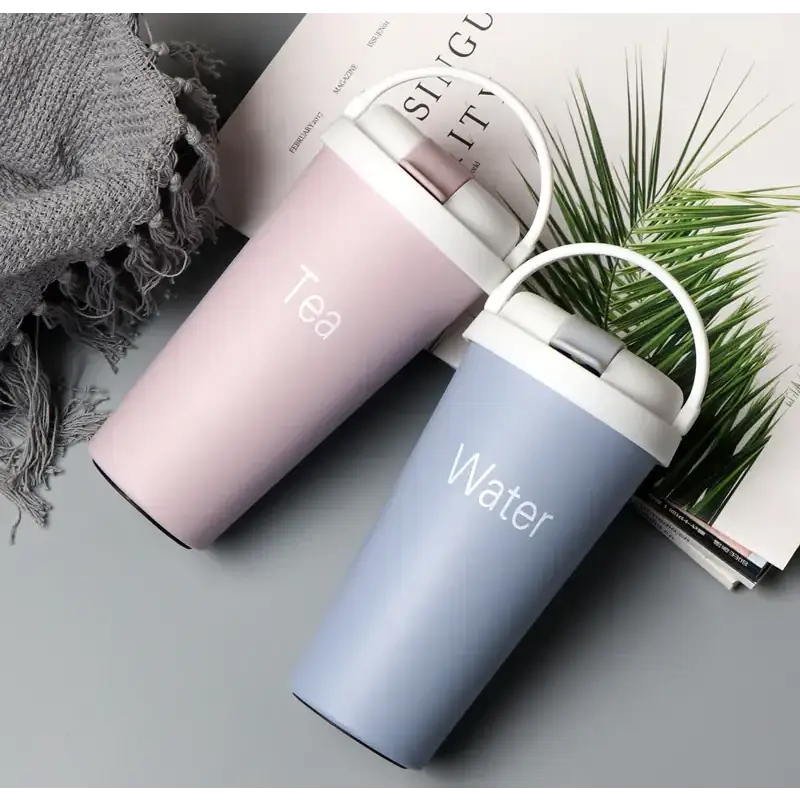 Two pastel-colored insulated travel mugs, one pink with ’tea’ printed on it and the other light blue with ’water,’ each featuring a white lid and handle.