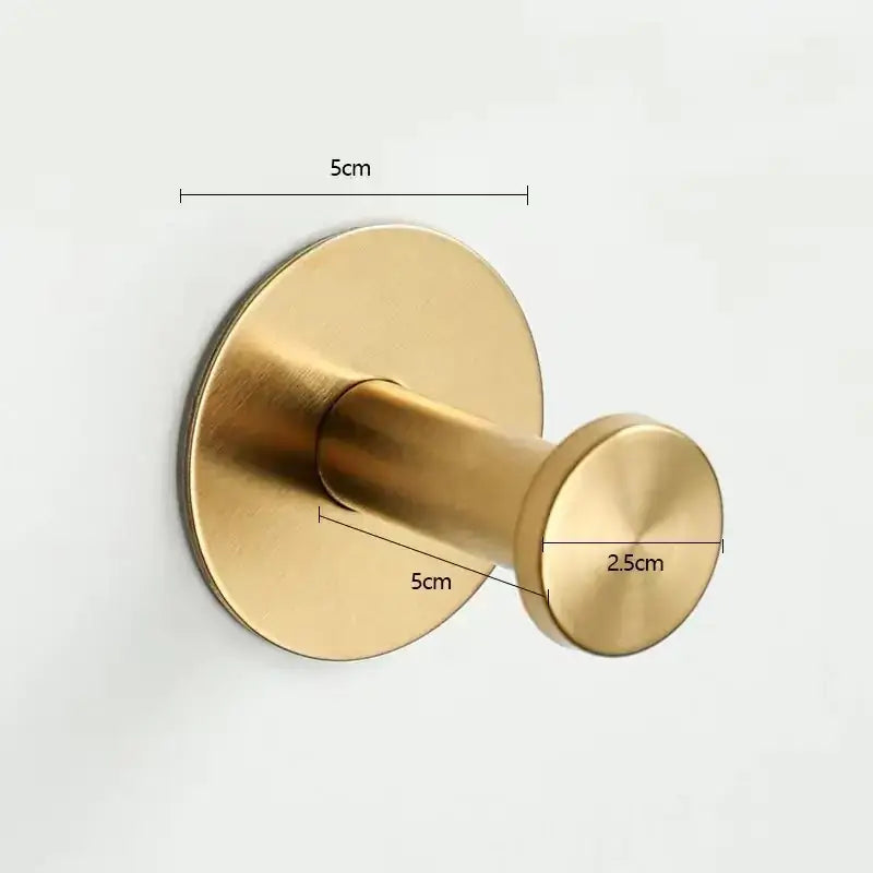 Gold-colored, circular wall-mounted hook with a brushed metallic finish and rounded head.