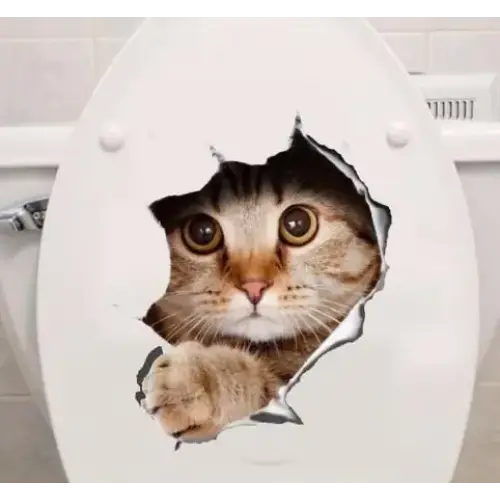 A realistic-looking tabby cat with wide, expressive eyes and a soft brown-and-gray coat peeks through a torn hole in the white toilet seat lid.