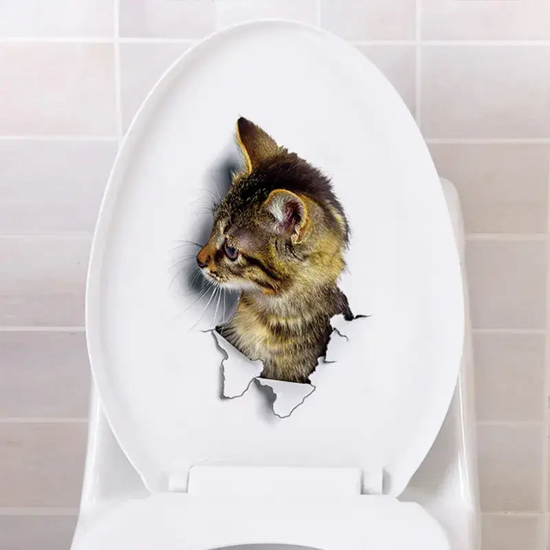 A realistic 3d cat sticker with brown and black fur, appearing to peek through a torn hole on a white toilet lid.