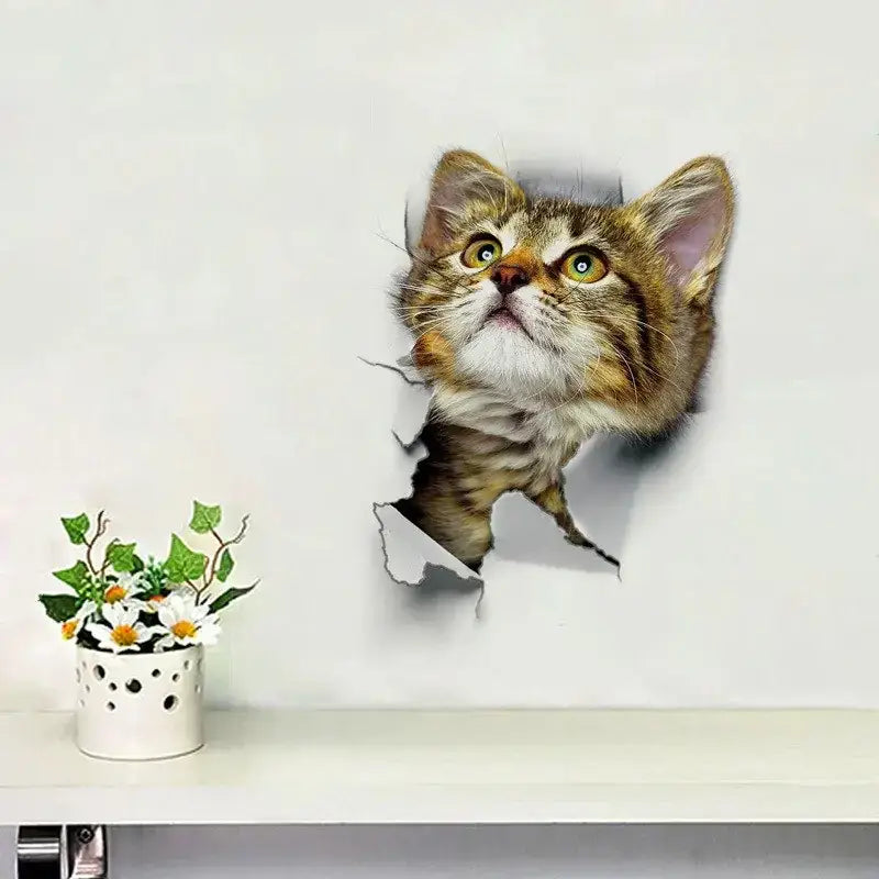 A realistic 3d wall decal of a tabby kitten with striking green eyes and soft brown fur peeking through a torn hole in the white wall.