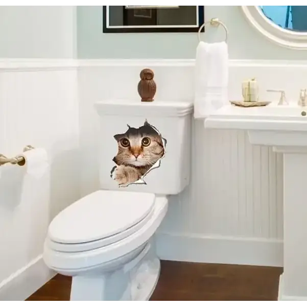 White ceramic toilet with a 3d cat face decal peeking through the tank lid.