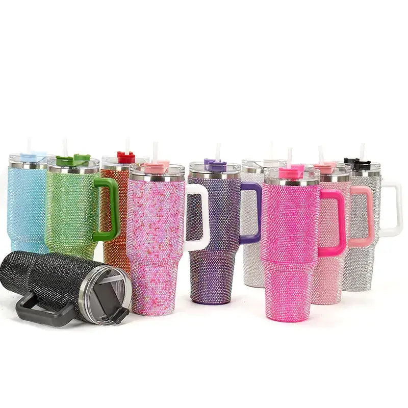 A collection of colorful, rhinestone-encrusted insulated tumblers with matching lids and handles in various hues including pink, purple, green, blue, orange, silver, and black.