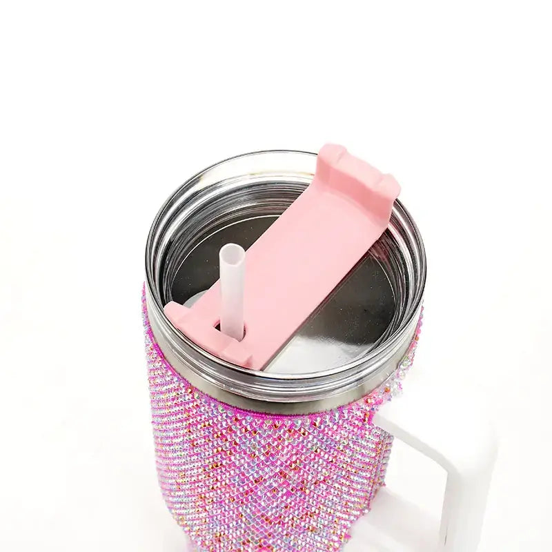 Pink rhinestone-encrusted insulated tumbler with a matching pink straw lid and white handle.