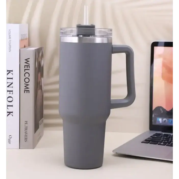 Gray insulated tumbler with a handle and clear lid featuring a straw.