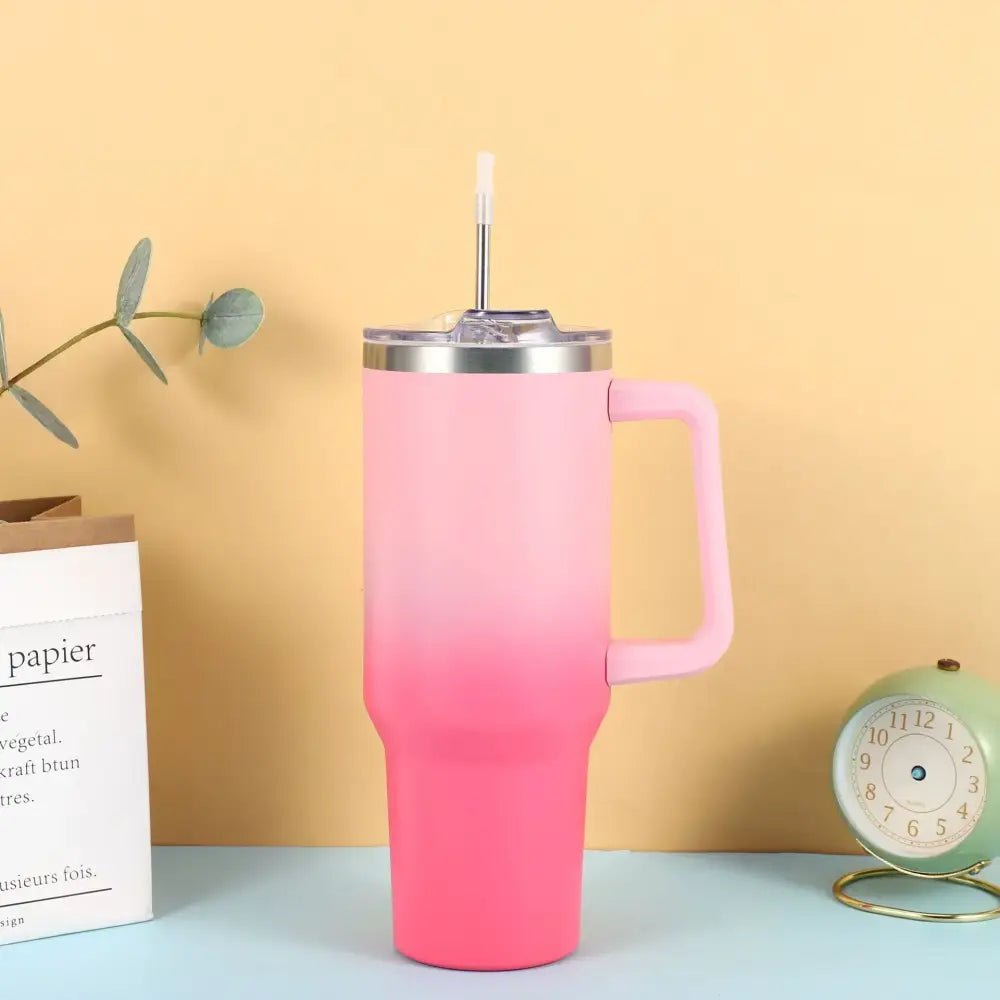Pink gradient stainless steel tumbler with a handle and straw.