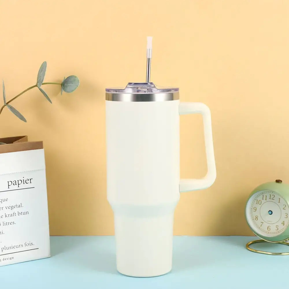 Cream-colored insulated tumbler with a stainless steel rim, clear lid, and integrated handle.