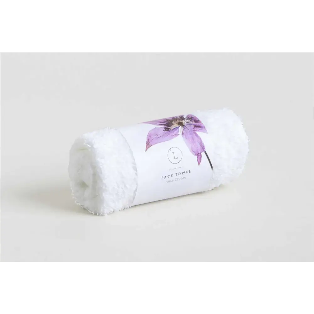 A plush white face towel, rolled neatly and adorned with a delicate purple clematis flower design on its label.