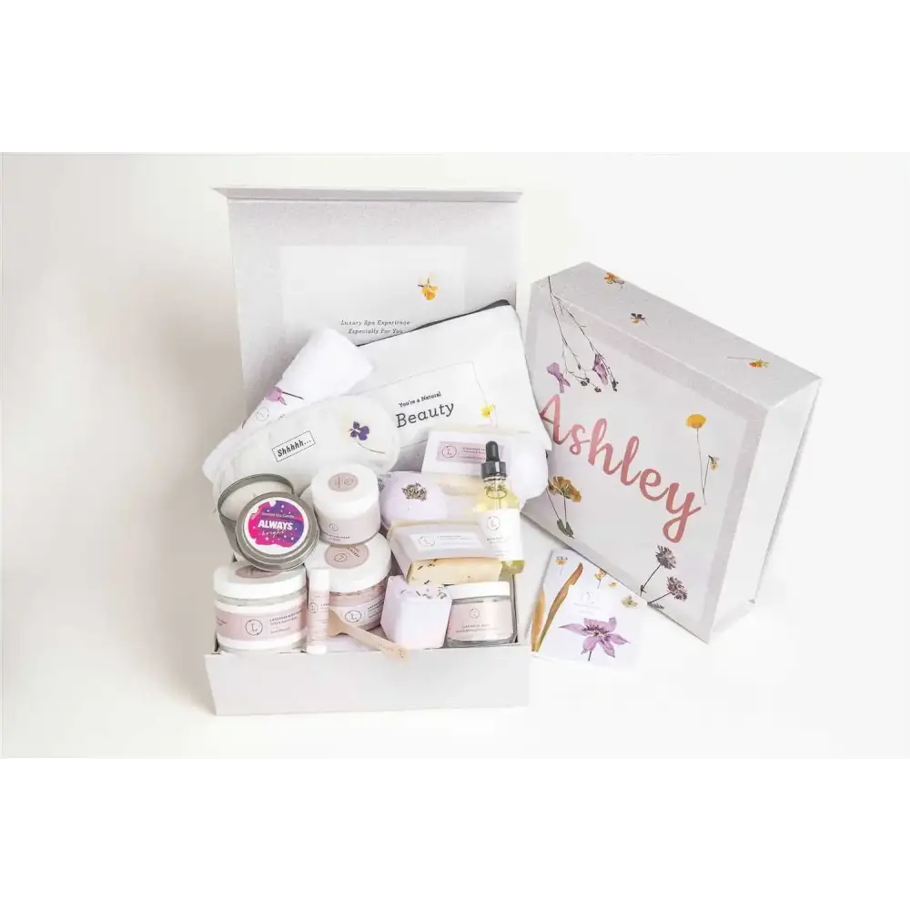White gift box with floral illustrations and the name ’ashley’ in pink cursive script, containing an assortment of beauty products.