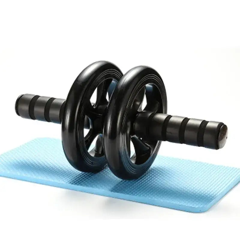 Black ab roller with textured grip handles and dual wheels resting on a light blue exercise mat.