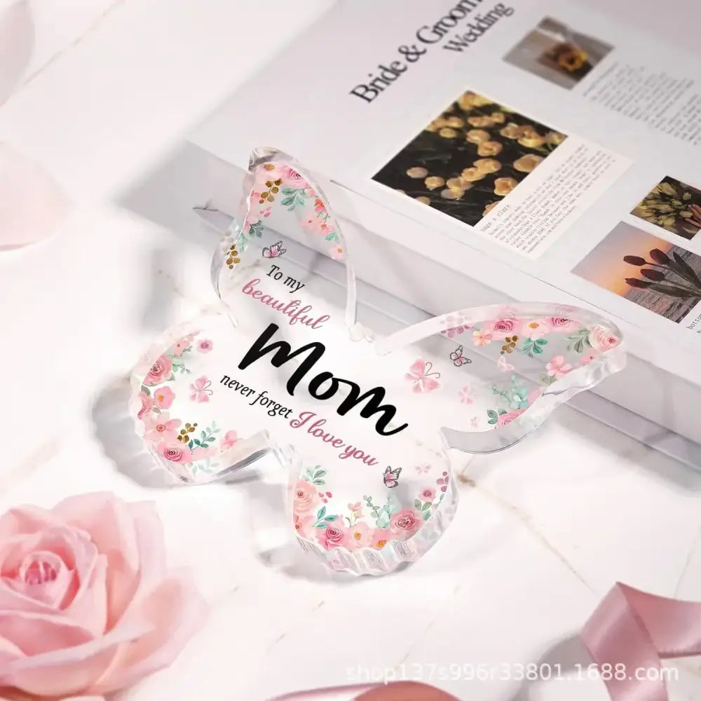 Clear acrylic butterfly-shaped ornament with pink and green floral patterns and the inscription ’to my beautiful mom, never forget i love you.’