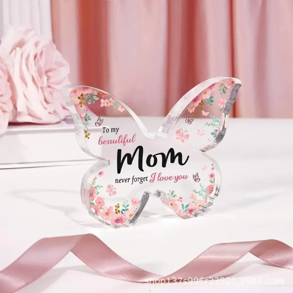 A clear acrylic butterfly-shaped keepsake with pink floral patterns and the inscription ’to my beautiful mom never forget i love you.’