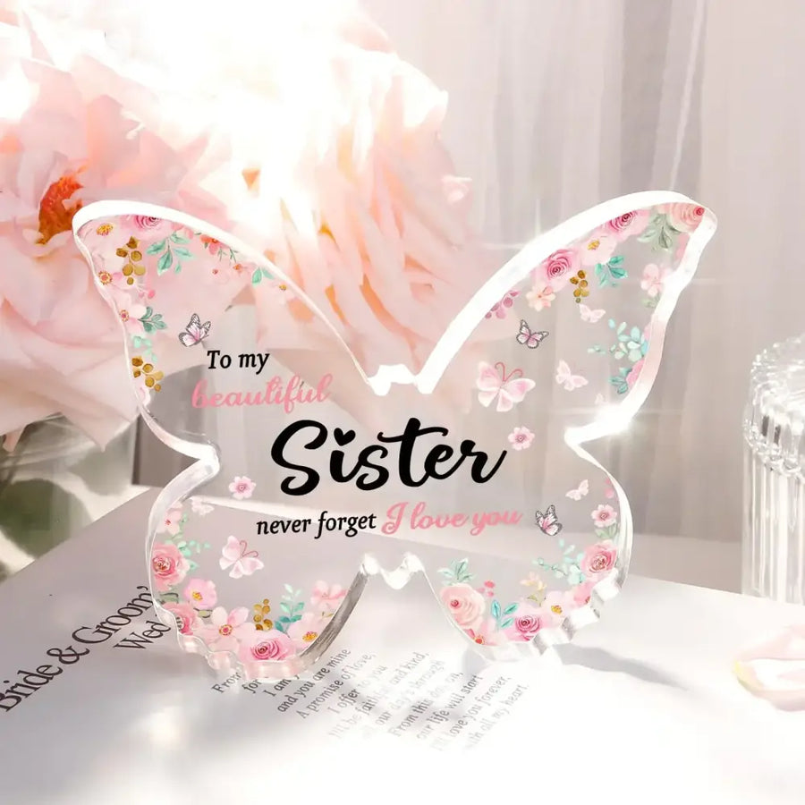 Clear acrylic butterfly-shaped keepsake with delicate pink and green floral patterns, small butterflies, and the inscription ’to my beautiful sister never forget i love you’ in black and pink script.