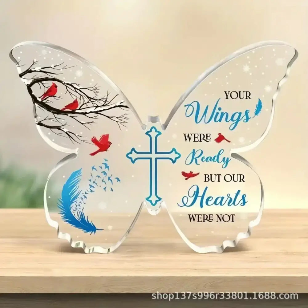 Clear acrylic butterfly-shaped decorative piece featuring red cardinals, blue feathers, and a central cross with the inscription ’your wings were ready but our hearts were not.’