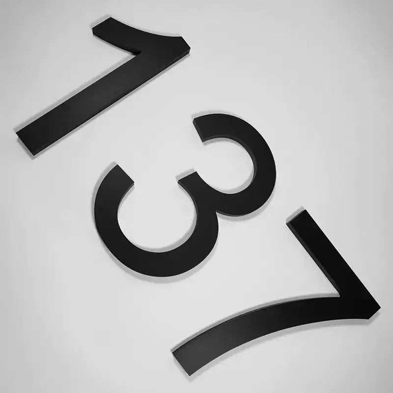 Black, three-dimensional house number plaques displaying the digits ’1’’, ’3’’, and ’7’’.