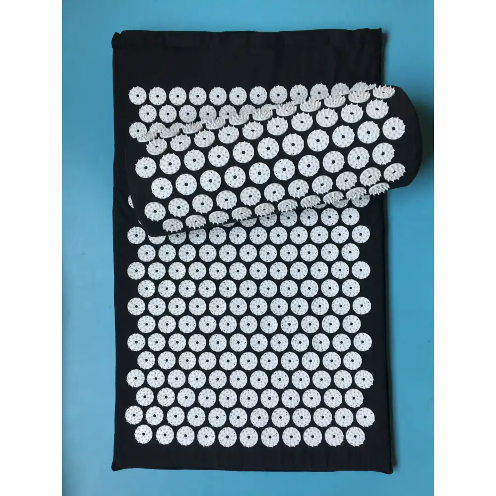 Black fabric mat with white circular acupuncture points arranged in a grid pattern, featuring one rolled-up section.