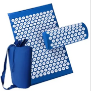 Blue acupressure mat set with white circular needles and matching cylindrical pillow, packaged in a blue drawstring bag.