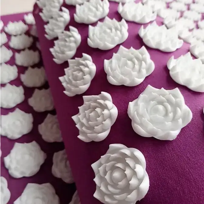 White rose-shaped spikes on a purple massage pad.