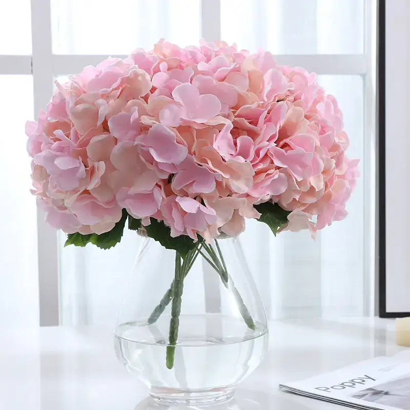 A lush arrangement of pink hydrangeas in a clear glass vase.