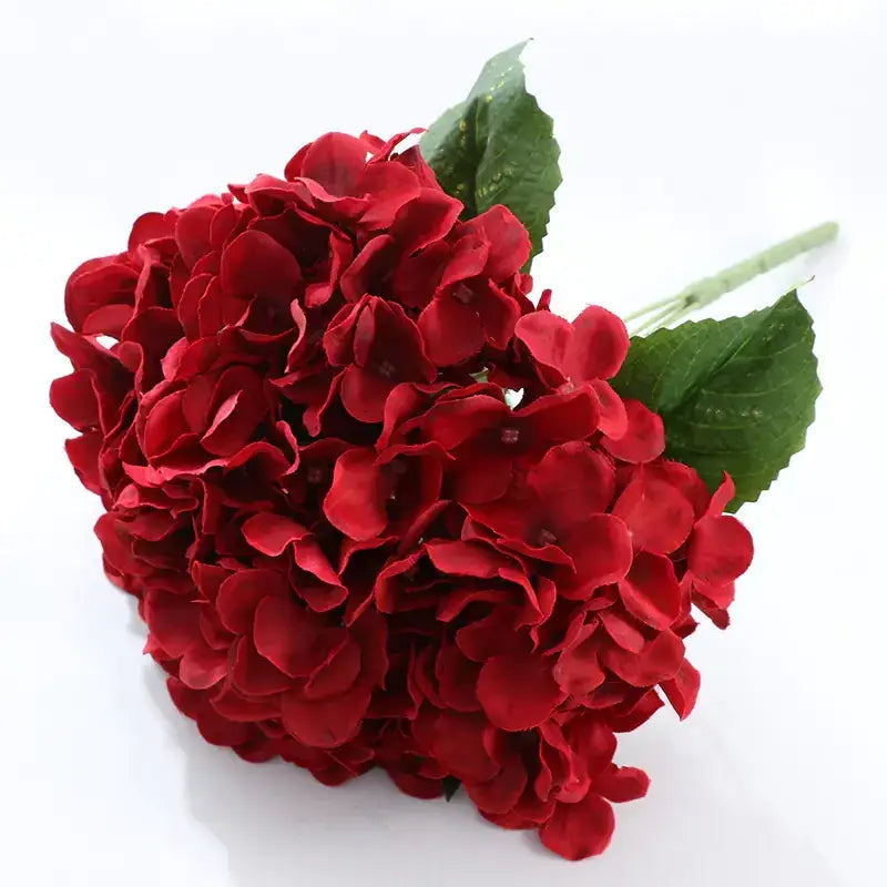 Vibrant red artificial hydrangea bouquet with lush, layered petals and glossy green leaves.