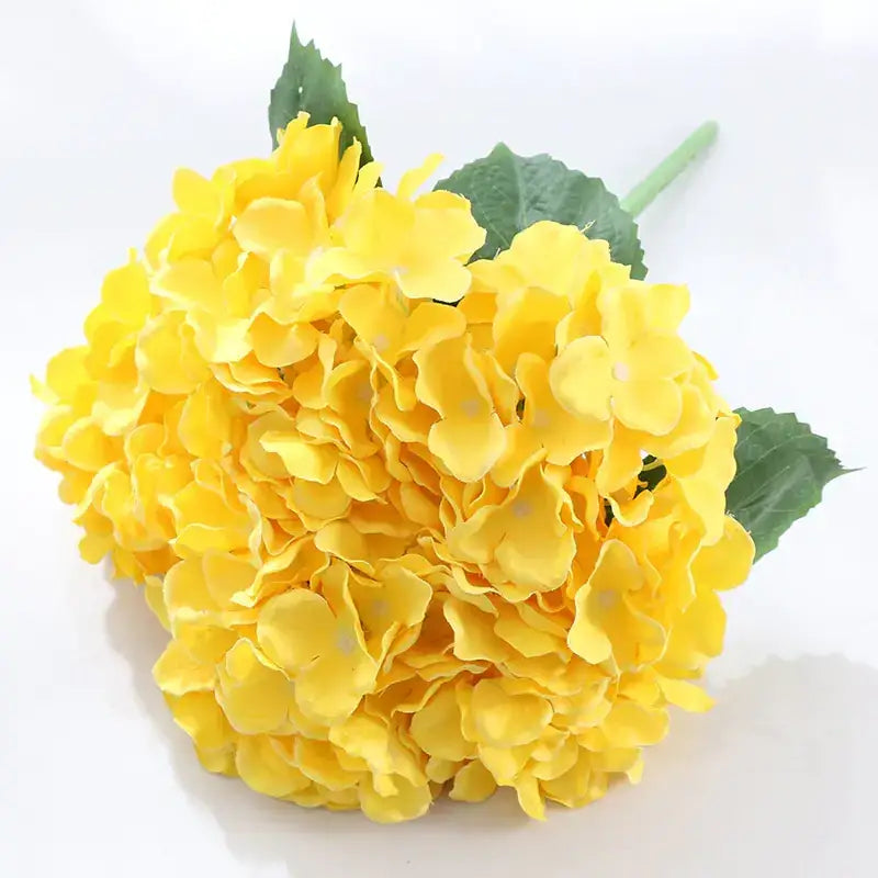 Vibrant yellow artificial hydrangea bouquet with lush green leaves and a slender stem.