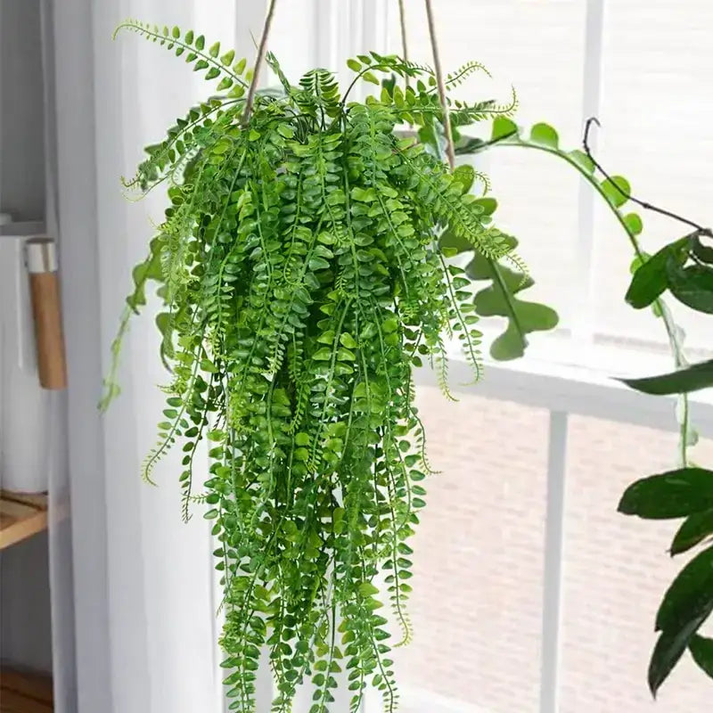 Green artificial fern hanging plant with cascading fronds and a natural-looking texture.