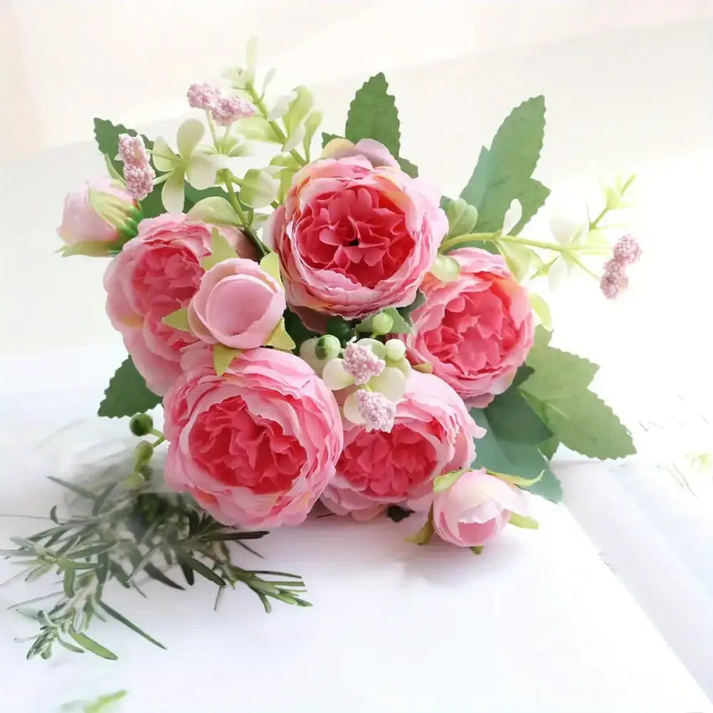 A delicate bouquet of pink peonies with soft, layered petals and interspersed green leaves.