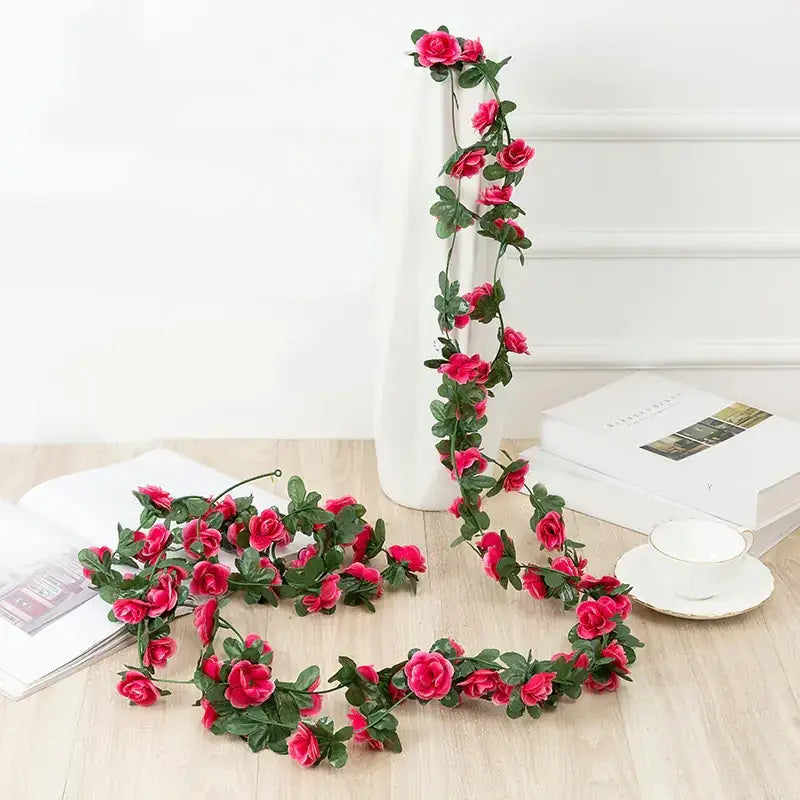 A vibrant pink artificial rose garland with lush green leaves, crafted from synthetic material.