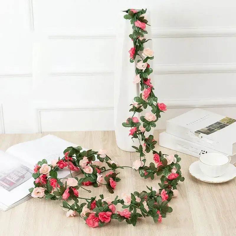 A delicate artificial floral garland featuring cascading pink and light peach roses intertwined with lush green leaves, crafted from synthetic fabric for a lifelike yet durable appearance.