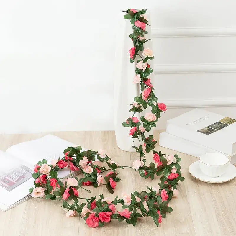 A delicate pink and green artificial rose garland, crafted from synthetic fabric to mimic the soft petals and lush leaves of real flowers.