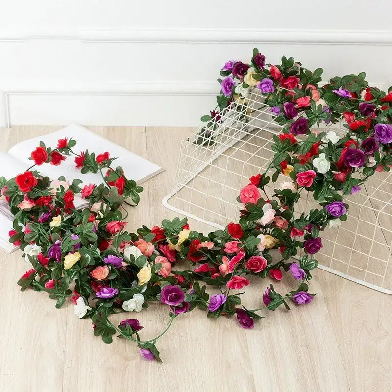 A vibrant, multi-colored artificial flower garland with realistic-looking roses and green leaves.