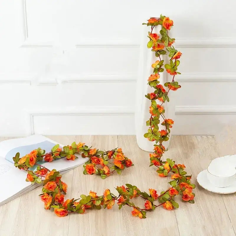 A vibrant orange and green artificial flower garland with realistic petals and leaves, designed for decorative display.