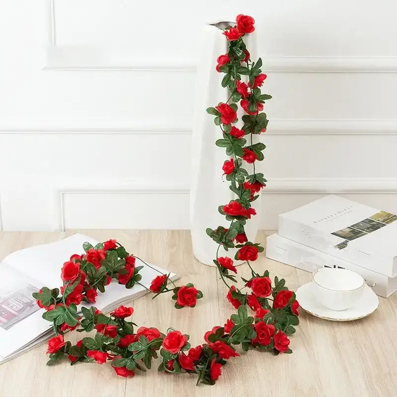 A vibrant red artificial rose garland with lush green leaves, crafted from synthetic material.