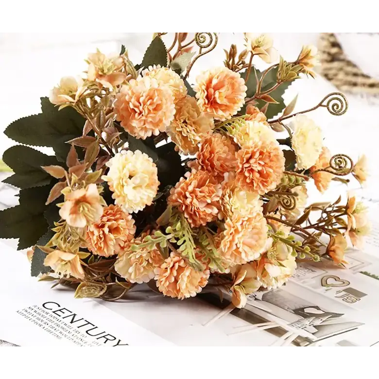A delicate bouquet of peach and cream-colored artificial flowers with green leaves and curly stems.