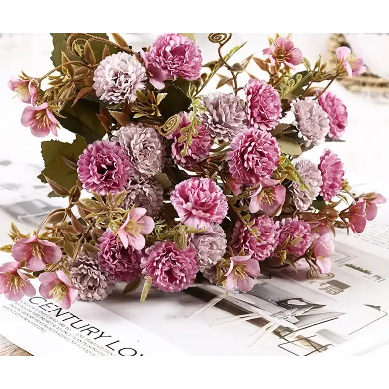 A bouquet of artificial flowers in shades of pink and lavender with detailed, layered petals and realistic green stems.